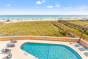 A pool area with a view of the beach and ocean. - Carolina Reef 202 - 1 Bedroom Ocean Front - Pool & Hot Tub (North Myrtle Beach)