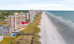 Un hotel frente al mar con varios pisos, vistas a la playa y un área de piscina.