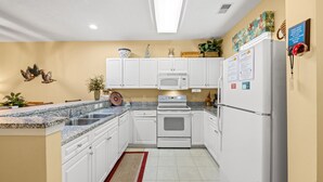 A kitchen with white cabinets, a microwave, a stove, and a refrigerator. - Ocean Keyes 4424 - Walk to Beach - 2 Bedroom Condo (North Myrtle Beach)