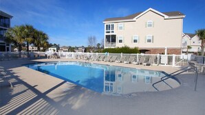 A swimming pool with a white fence and lounge chairs, surrounded by a building with a balcony. - Ocean Keyes 4424 - Walk to Beach - 2 Bedroom Condo (North Myrtle Beach)