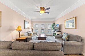A living room with a ceiling fan, two sofas, a coffee table, and a lamp.