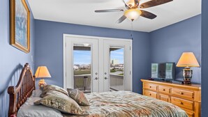 A bedroom with a bed, wooden dresser, television, and a ceiling fan. - Barbee's Flamingo-4 Bedroom/2 Bath Channel House in Cherry Grove (North Myrtle Beach)