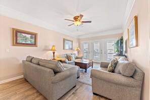 Un salon avec deux canapés, une table basse et un ventilateur de plafond.
