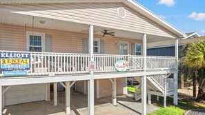 A two-story house with a covered porch and a sign for Elliott Realty Rental. - Barbee's Flamingo-4 Bedroom/2 Bath Channel House in Cherry Grove (North Myrtle Beach)