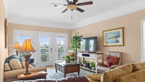 A living room with a sofa, a coffee table, a TV, and a ceiling fan. - Barbee's Flamingo-4 Bedroom/2 Bath Channel House in Cherry Grove (North Myrtle Beach)