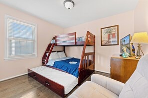 Une chambre avec un lit superposé, un bureau avec une lampe et une chaise.