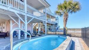 A swimming pool with a metal ladder, lounge chairs, and a palm tree. - Barbee's Flamingo-4 Bedroom/2 Bath Channel House in Cherry Grove (North Myrtle Beach)