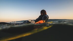 En person som sitter på en surfbräda i havet.