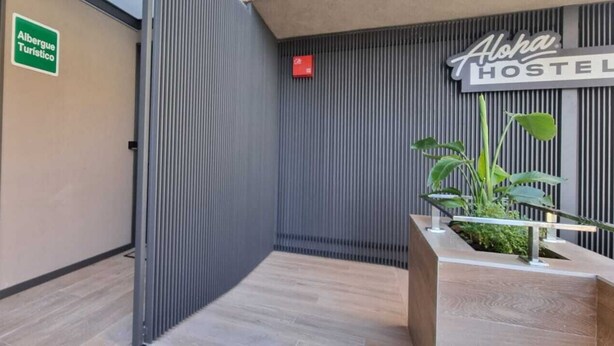 En hostelentré med en skylt som visar ”Albergue Turístico” och ”Aloha Hostel”.