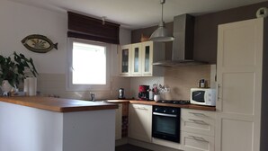 A kitchen with a central island, a stove, a microwave, and cabinets. - House 6 persons near Port de Doëlan / 2 stars tourism (Clohars-Carnoët)