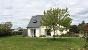 A single-story house with a sloped roof, a small porch, and a well-maintained lawn. - House 6 persons near Port de Doëlan / 2 stars tourism (Clohars-Carnoët)