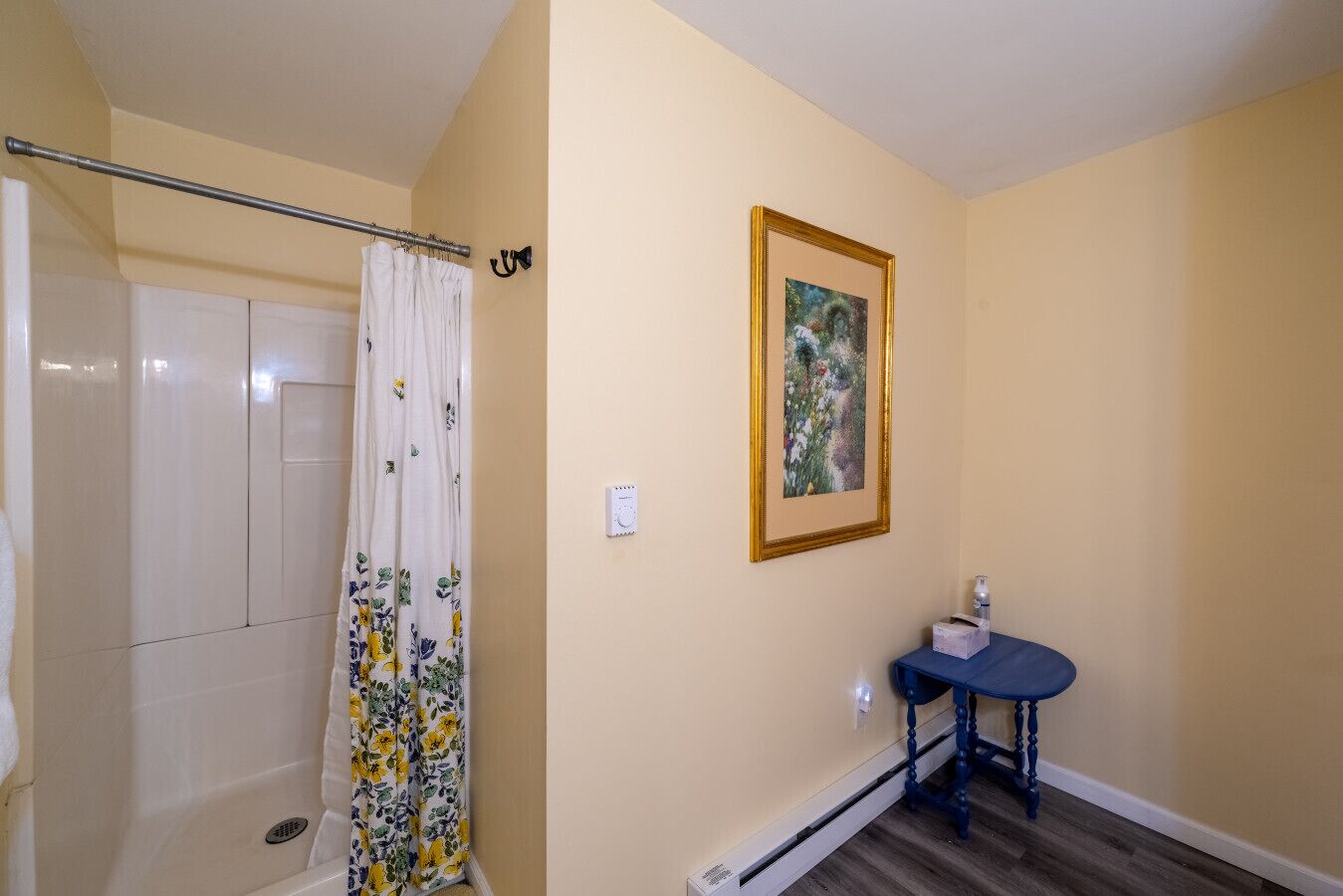 Ein Badezimmer mit Dusche, Toilette, Waschbecken und einem gerahmten Bild an der Wand.