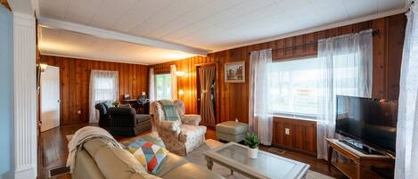 A cozy living room with a sofa, armchairs, a coffee table, and a television.