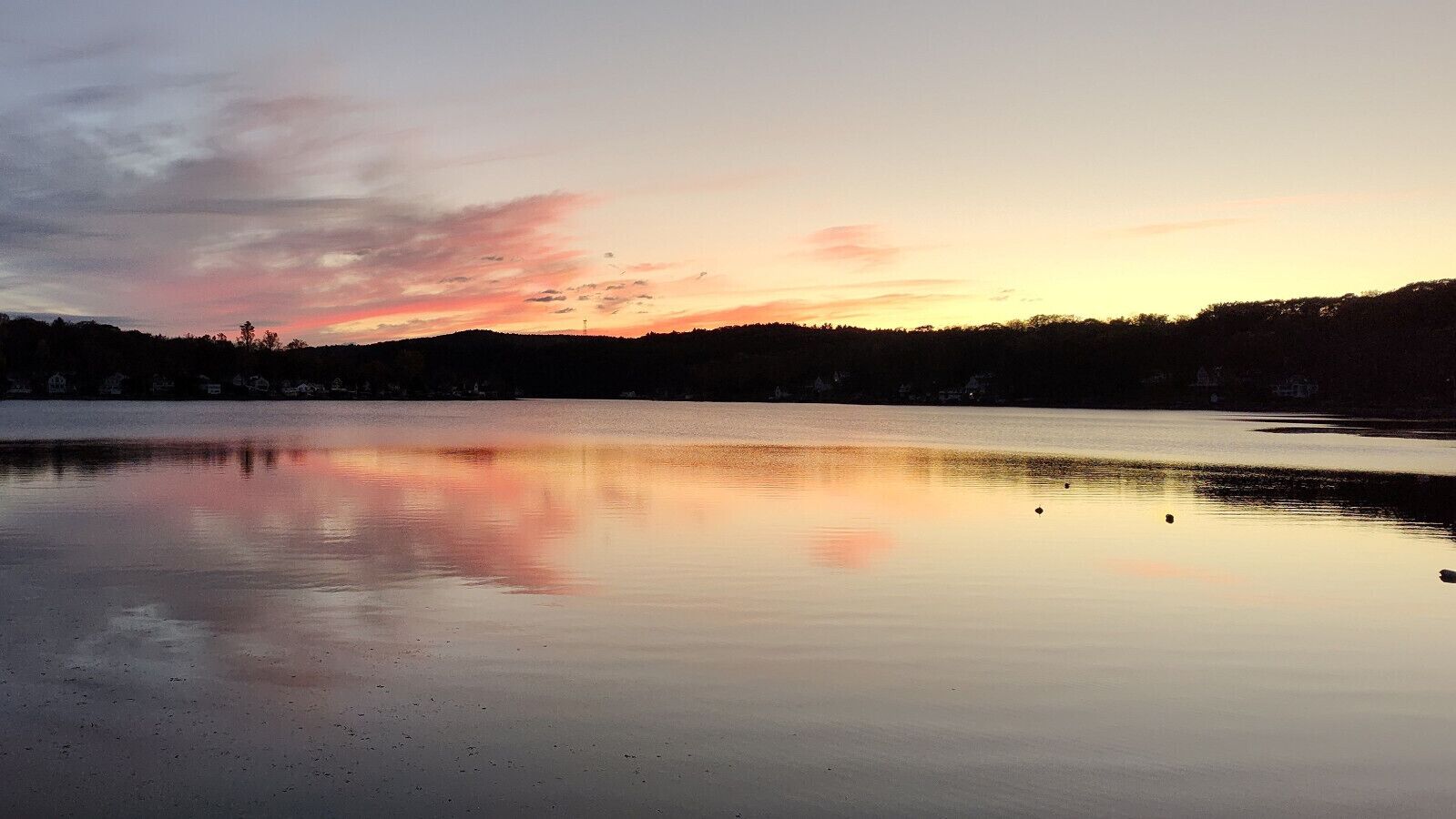 Un lago tranquilo al atardecer con un reflejo claro del cielo.