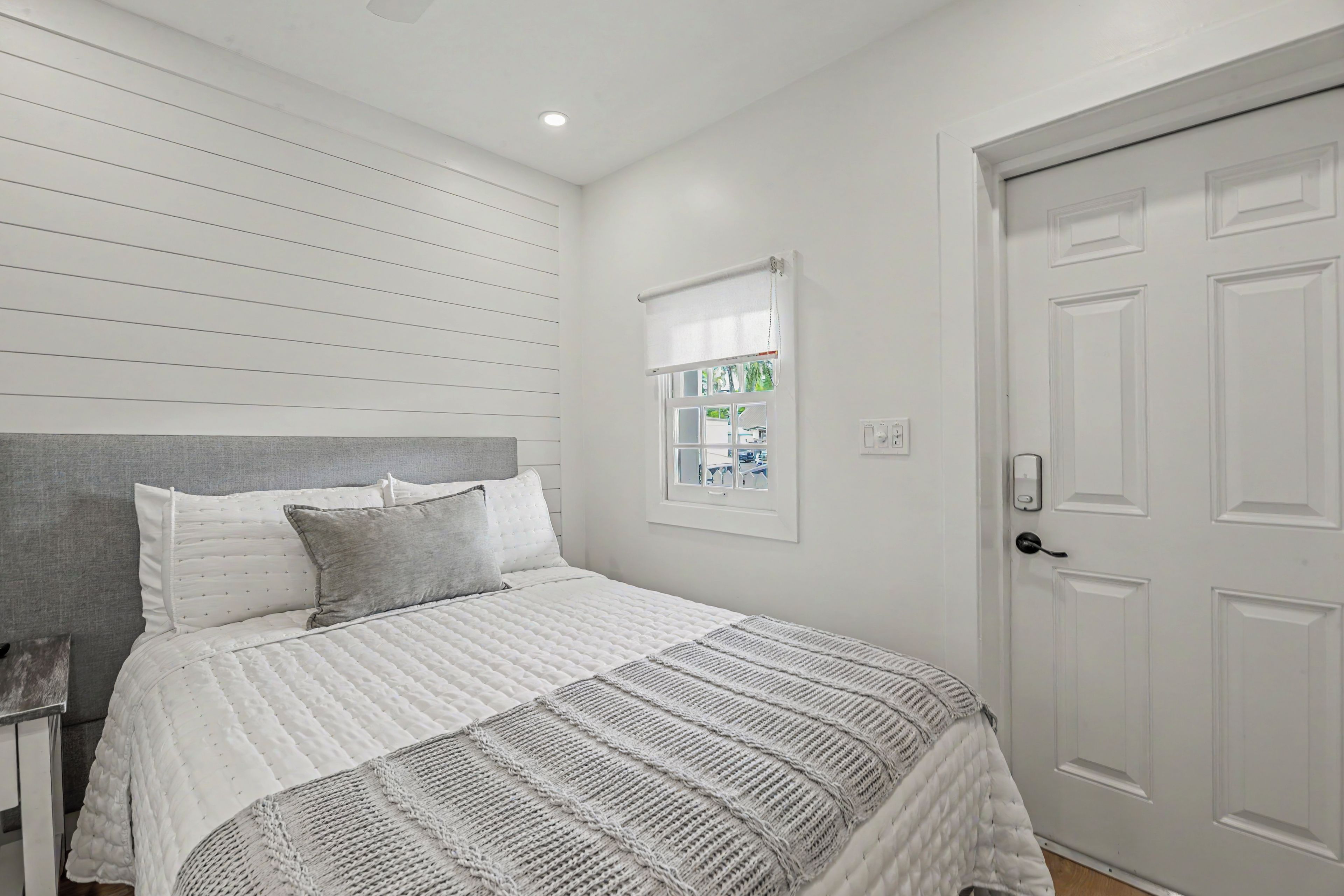 A bedroom with a bed, a window with a view, and a door.