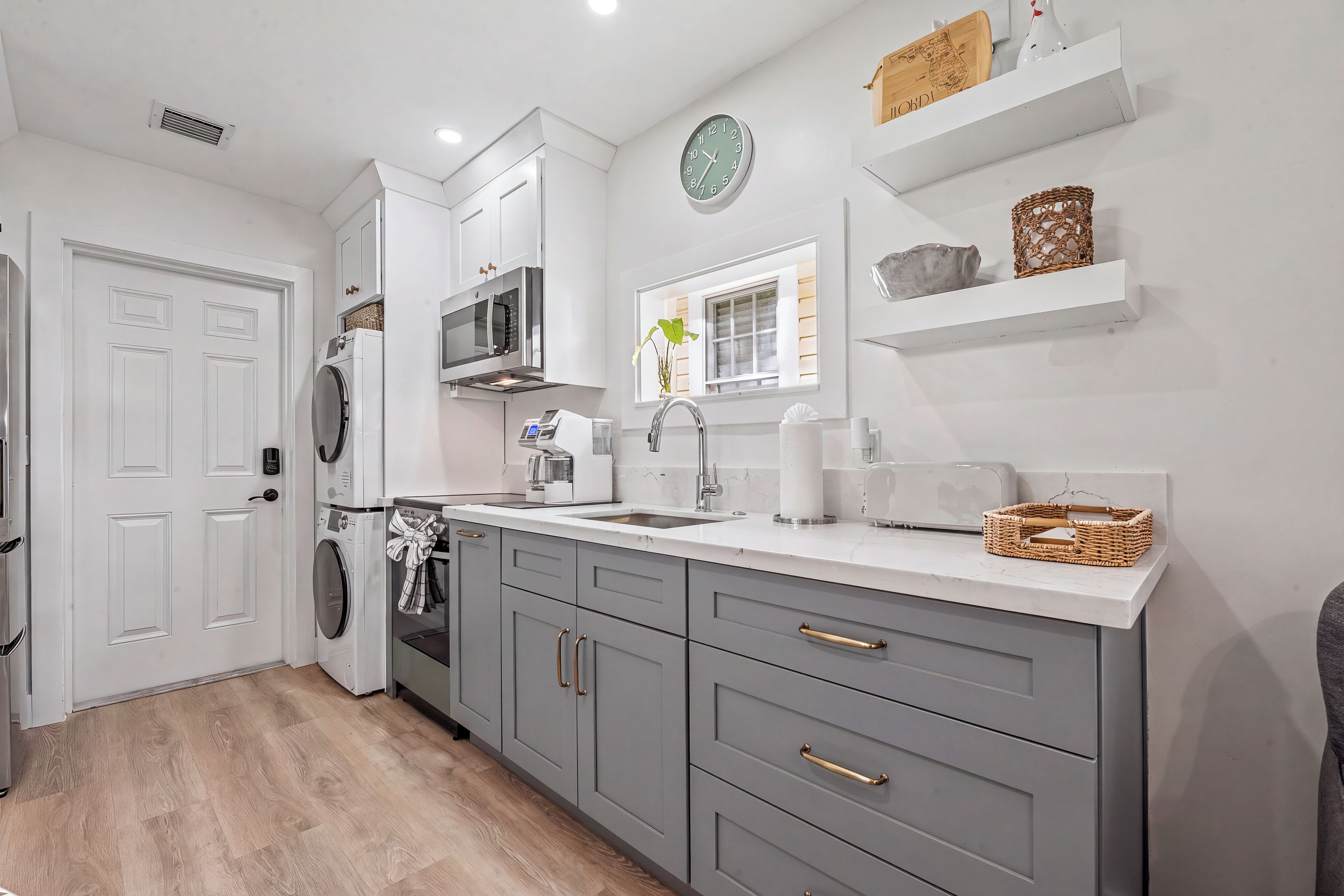 A modern kitchen with a built-in washing machine, a microwave, and a sink.