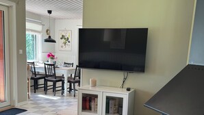 Un salon doté d’une cheminée, d’un téléviseur fixé au mur et d’un coin repas avec une table et des chaises.