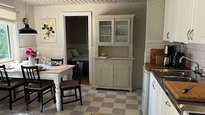 Une cuisine avec des meubles blancs, un carrelage à motifs et un coin repas comprenant des chaises et une table.