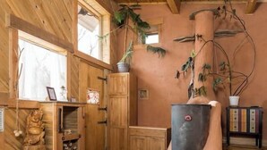 A rustic interior with wooden beams, a fireplace, and a shelf with a statue. - Off-Grid Cottage at Granny Flats (Spearfish)
