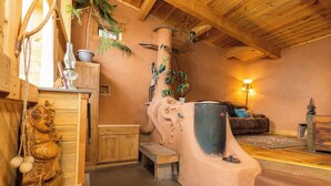 A rustic interior with wooden beams, a stone fireplace, and a cozy seating area. - Off-Grid Cottage at Granny Flats (Spearfish)