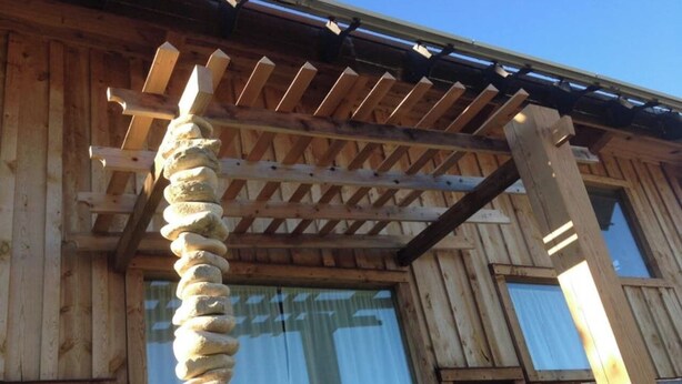 A wooden building with a stone pillar, wooden beams, and windows. - Off-Grid Cottage at Granny Flats (Spearfish)