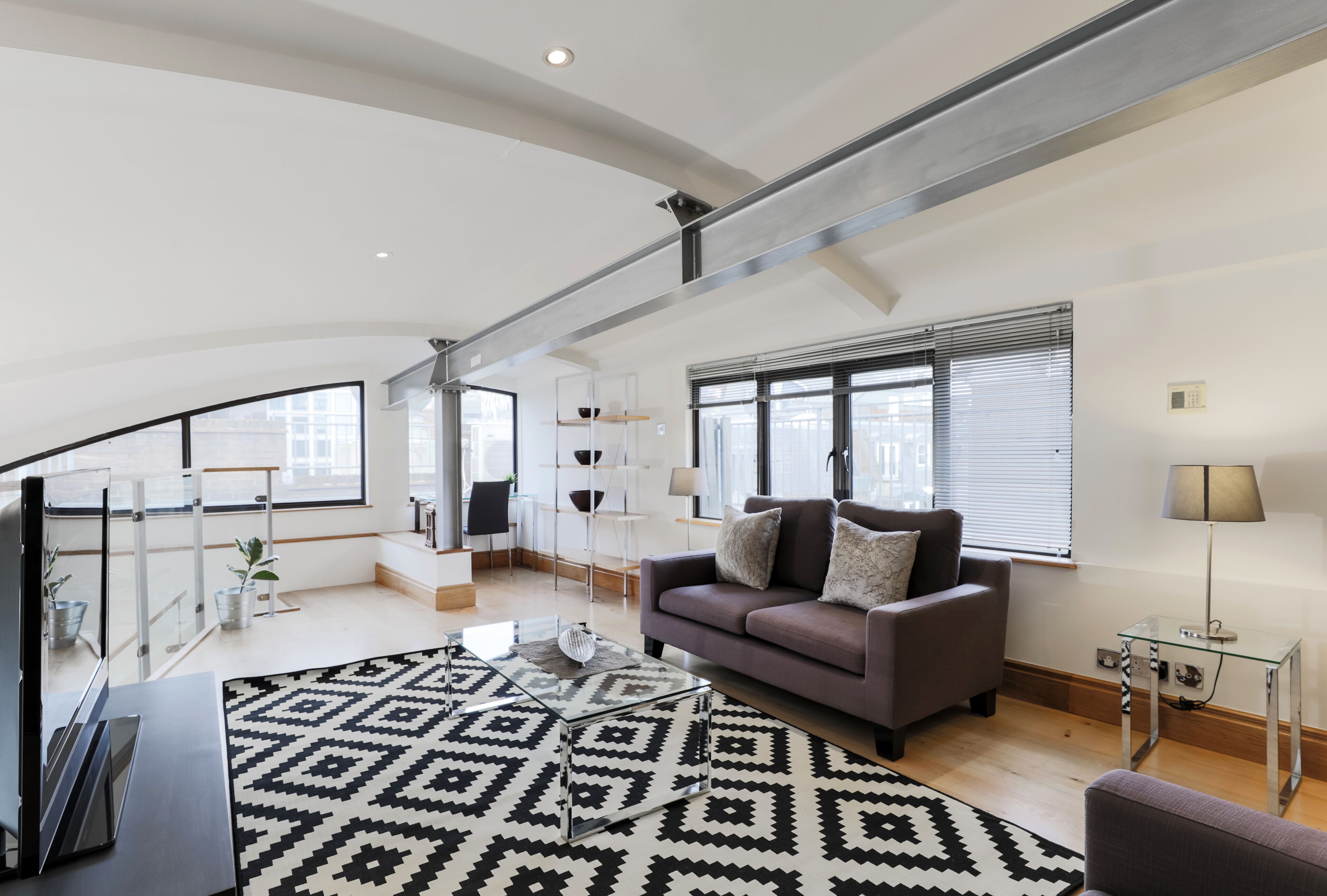 A modern living room with a sofa, coffee table, and patterned rug.