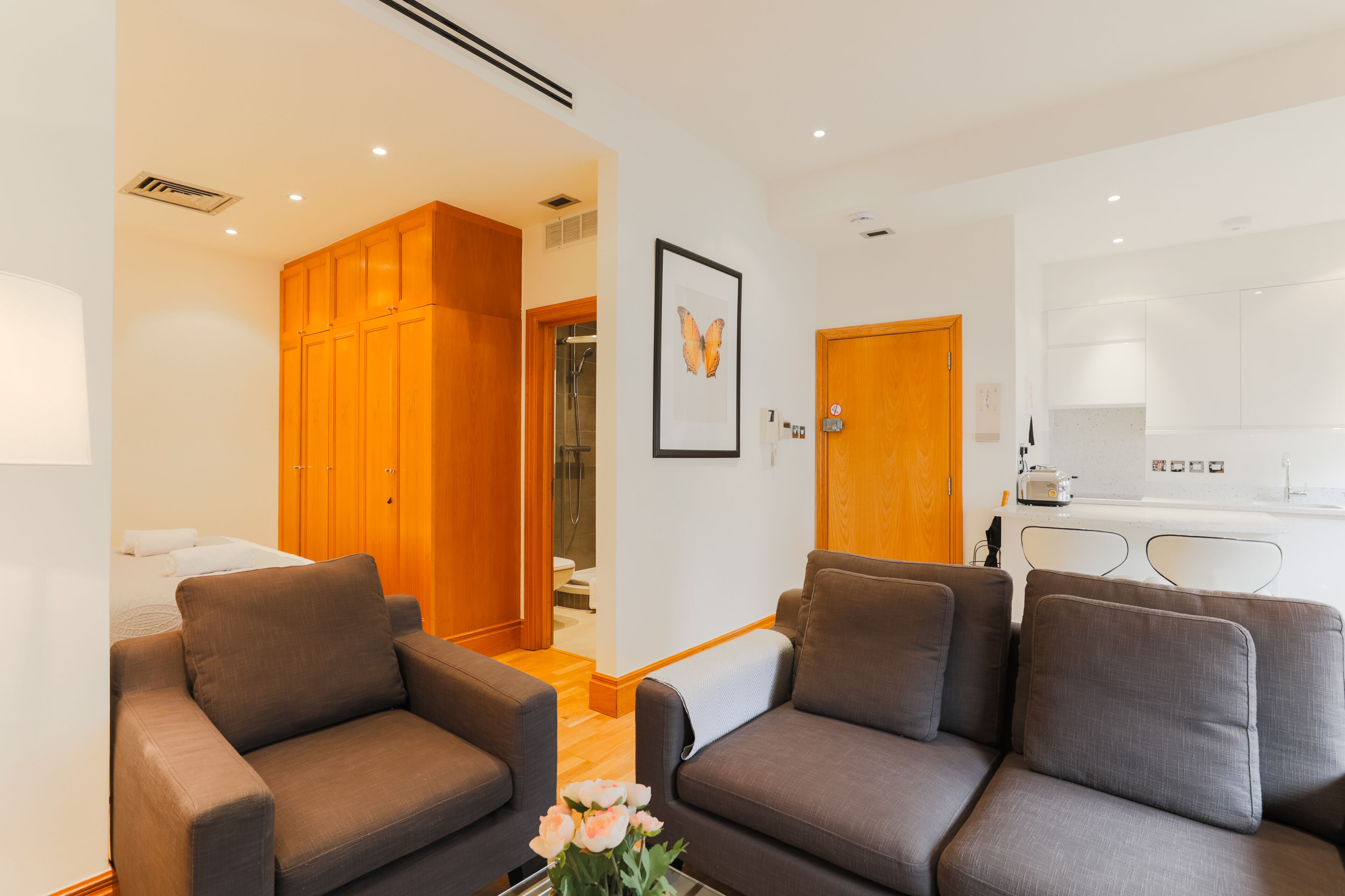 A modern living room with two sofas, a coffee table with flowers, and a wooden wardrobe.