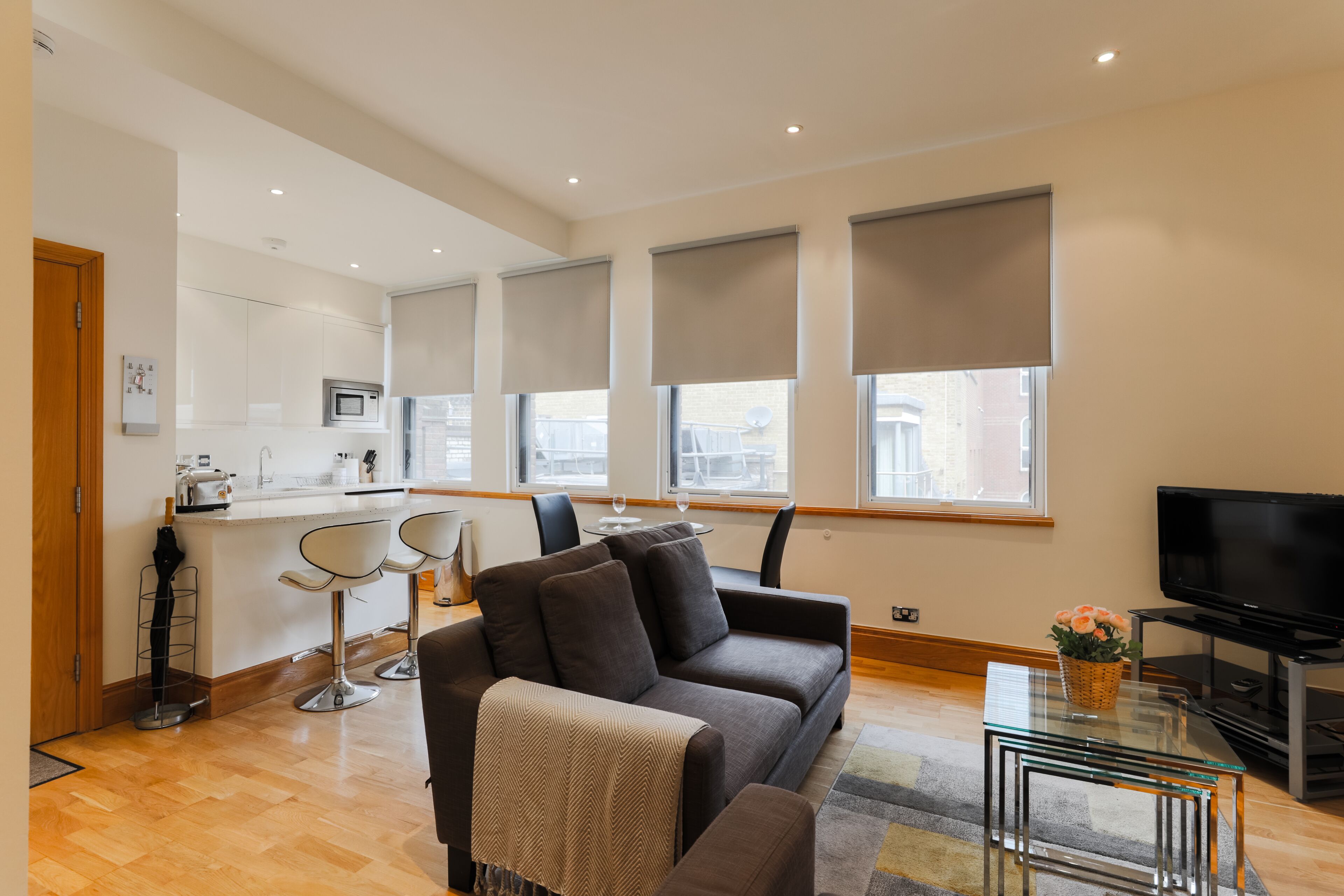 Uma sala de estar moderna com um sofá, uma mesa de centro de vidro e uma televisão.