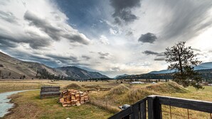 Paisaje rural con una cerca de madera, un montón de leña y un río.