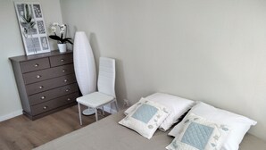 Une chambre à coucher comprenant un lit, une commode, une chaise et une étagère fixée au mur.