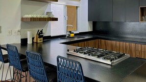 Een moderne keuken met een centraal eiland, barstoelen en inbouwmeubels.