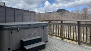 Een hottub op een houten terras met uitzicht op bergen en bomen.
