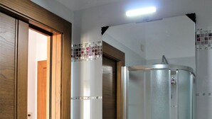 Un baño con un lavamanos blanco, un espejo y una repisa de vidrio.