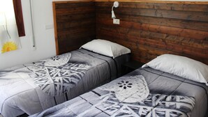 Una habitación con dos camas, cada una con cabecero de madera y almohada blanca.