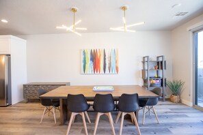 Eine moderne Küche mit einem Holztisch, schwarzen Stühlen und einem farbenfrohen abstrakten Gemälde an der Wand.