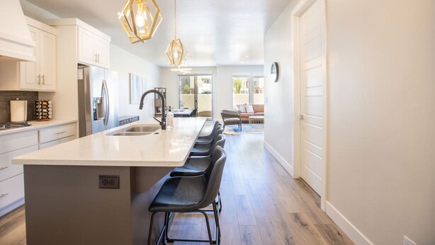 A modern kitchen with white cabinetry, a large island with bar stools, and pendant lighting. - Rooftop Hot Tub & Heated Pool (Washington)