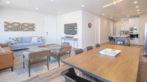 A modern living room with a sofa, coffee table, and dining table. There is a kitchen area with a microwave and refrigerator. - Rooftop Hot Tub & Heated Pool (Washington)