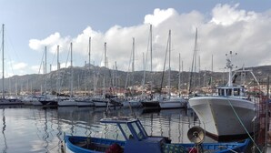 Un port de plaisance avec plusieurs bateaux amarrés, un petit bateau au premier plan et un paysage montagneux en arrière-plan.