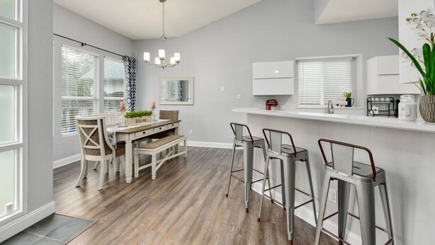 A modern kitchen with a dining area, featuring a wooden table, bar stools, and a chandelier. - Water Well Wonder|Near Apple & Domain|Pet Friendly (Austin)