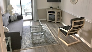 A living room with a sofa, a chair, a coffee table, a TV, and a small cabinet. - Uncrowded Beachfront Getaway with an Ocean View (Murrells Inlet)