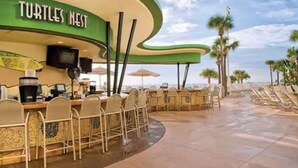 Un restaurant situé en bord de mer, appelé « Le Nid des Tortues », avec une terrasse et des palmiers en arrière-plan.