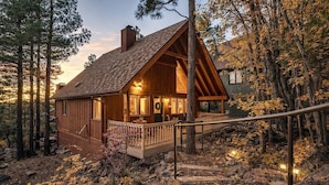 Une cabane rustique avec une façade en bois, une véranda et un escalier menant à l’entrée.