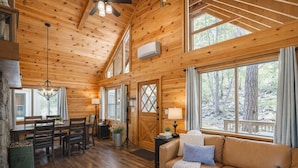 L’intérieur d’un chalet en bois comprend un coin repas, un canapé et de grandes fenêtres.