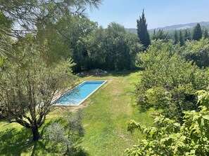 A rectangular swimming pool surrounded by lush greenery and trees. - Studio Avec Piscine (Saint veran/Orgon)