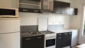 A modern kitchen with a gas stove, oven, microwave, and built-in cabinets. - Studio Avec Piscine (Saint veran/Orgon)