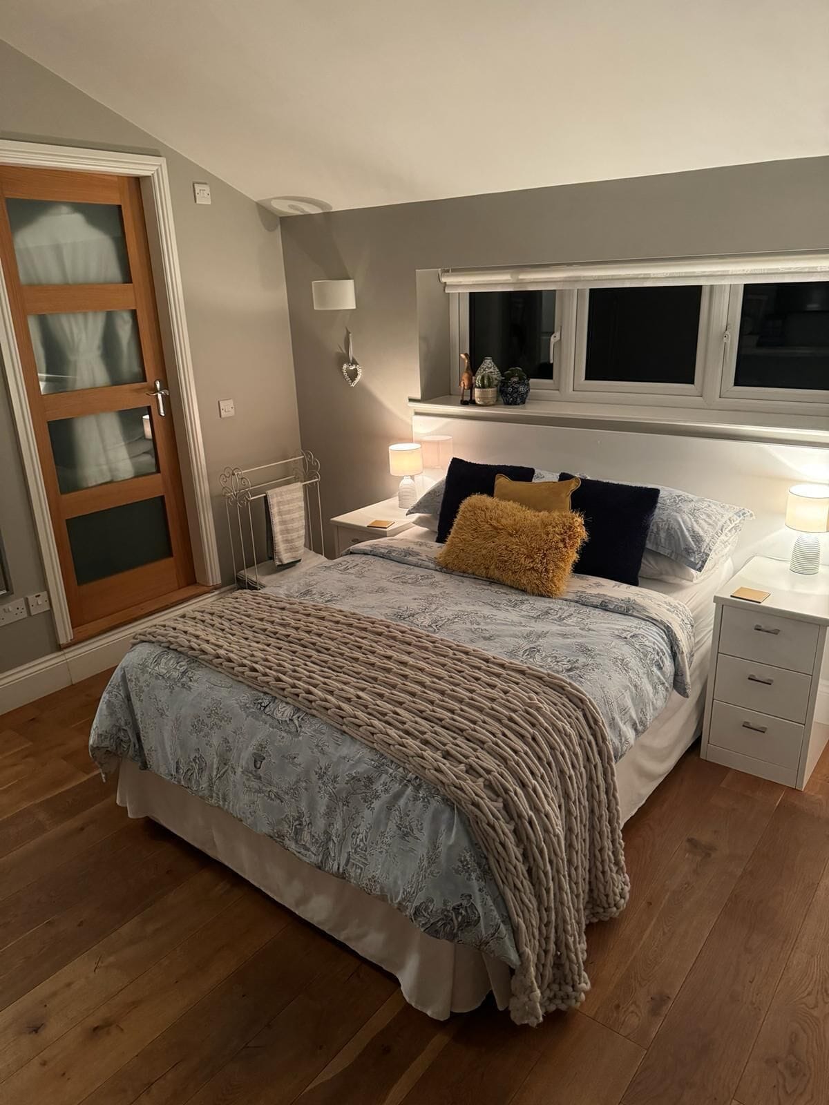 A bedroom with a bed, bedside tables, a window, and a door.