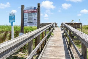 A wooden boardwalk leading to a beach area with informational signs.