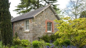Une maison en pierre avec un toit en pente et une fenêtre dotée d’un cadre rouge.