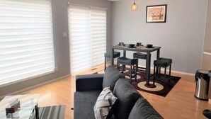 Un salon moderne avec un canapé gris, une table à manger avec des chaises et une table basse.