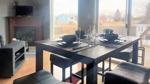 Un coin repas avec une table en bois foncé, dressée pour deux personnes, entourée de chaises noires.
